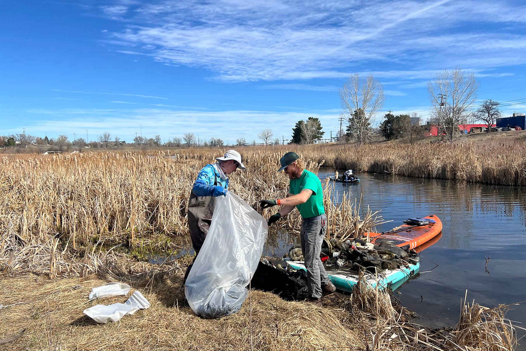Two men pick up garbage at a Polar Planet lake cleanup in Denver